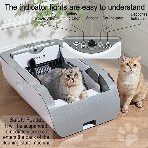 Automatic cat litter box with indicator lights and two cats nearby.