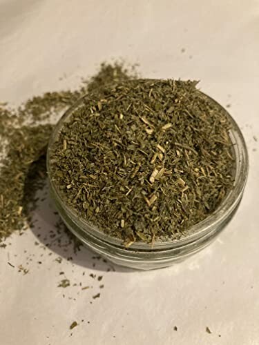 Jar filled with dried herbs on a white surface